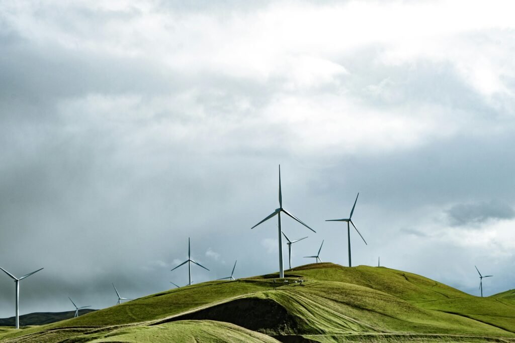 Wind turbines on lush hills with a dramatic cloudy sky, symbolizing clean energy and sustainability.